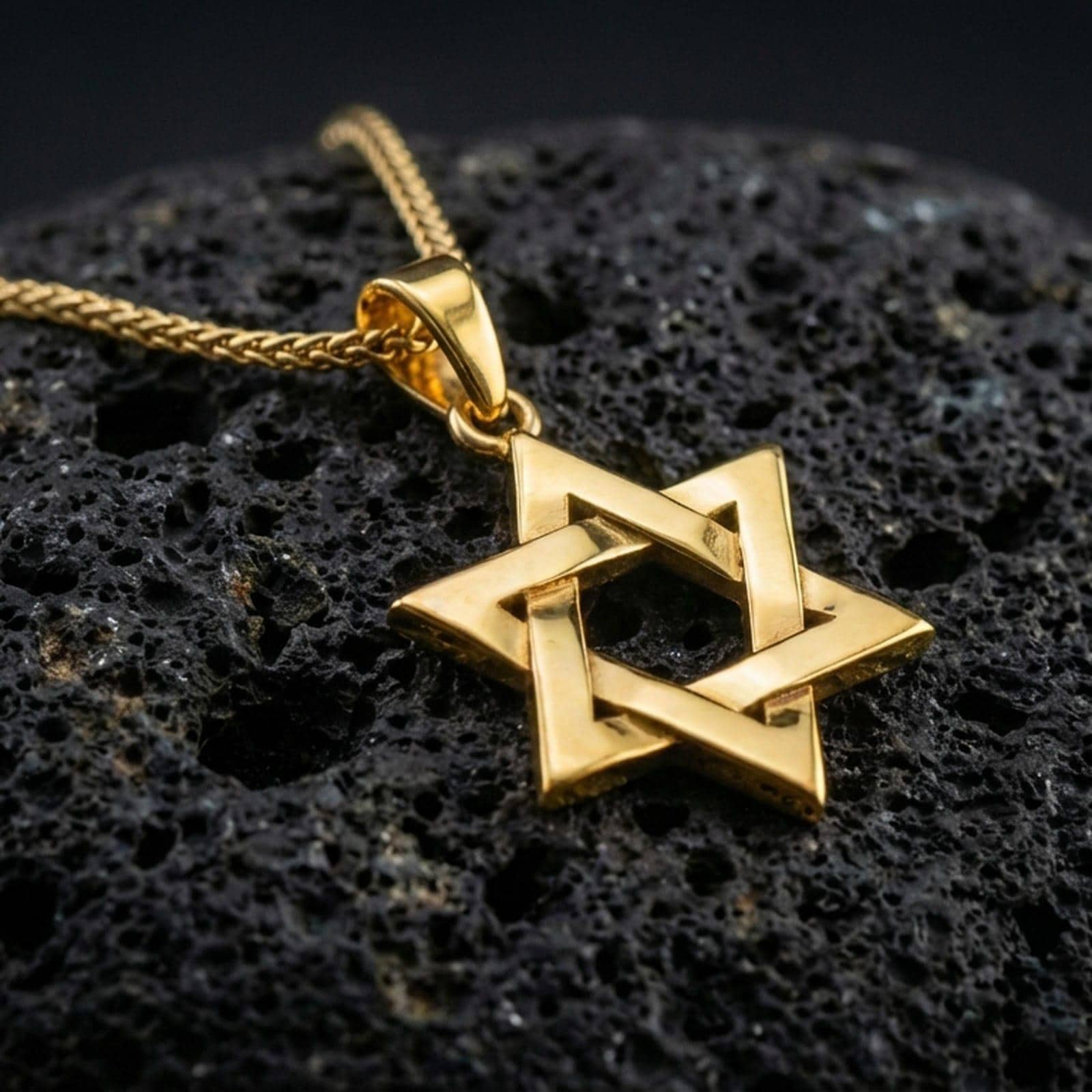 Gold plated Star of David pendant with interwoven hexagram shape, sharp geometric edges, and classic spiritual symbolism showcased on black volcanic rock in a refined macro jewelry image