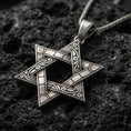 Load image into Gallery viewer, Oxidized Star of David pendant with engraved ornamental lines and open hexagram silhouette displayed on dark volcanic rock in a close-up luxury jewelry composition
