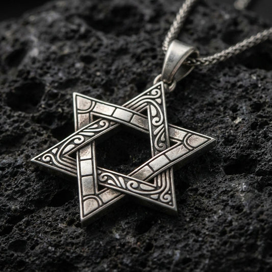 Oxidized Star of David pendant with engraved ornamental lines and open hexagram silhouette displayed on dark volcanic rock in a close-up luxury jewelry composition