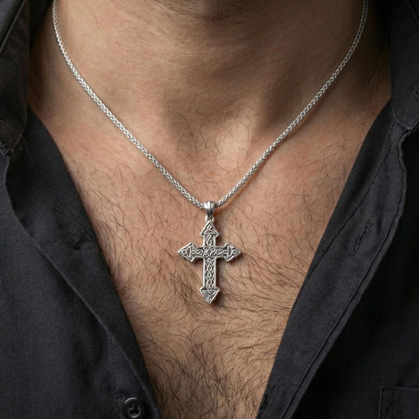 Polished silver cross necklace with interwoven Celtic detailing worn on the neck in a close lifestyle frame, highlighting the openwork silhouette and symbolic pattern