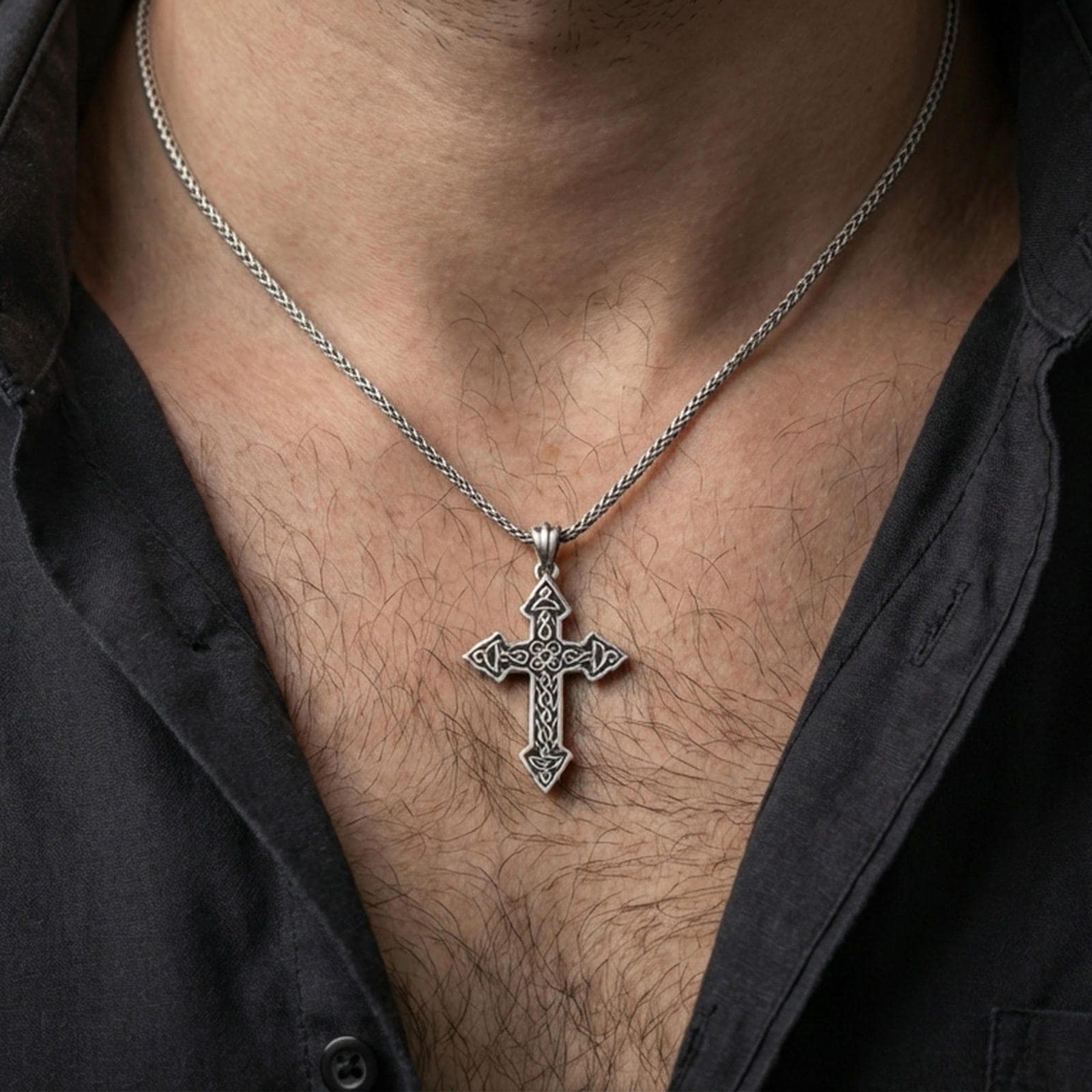 Oxidized Celtic cross pendant with intricate knotwork worn on the neck in a lifestyle jewelry shot, styled against the chest for a bold and meaningful look