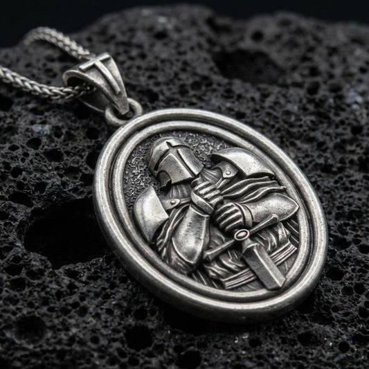 Oxidized Knight Templar pendant with crusader helmet, sword detail, and oval rotating medallion design displayed on dark volcanic rock in a close-up luxury jewelry composition