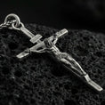Load image into Gallery viewer, Oxidized sterling silver crucifix pendant on volcanic stone, macro close-up highlighting the deepened relief of the corpus, wood-grain cross texture, and antique contrast.
