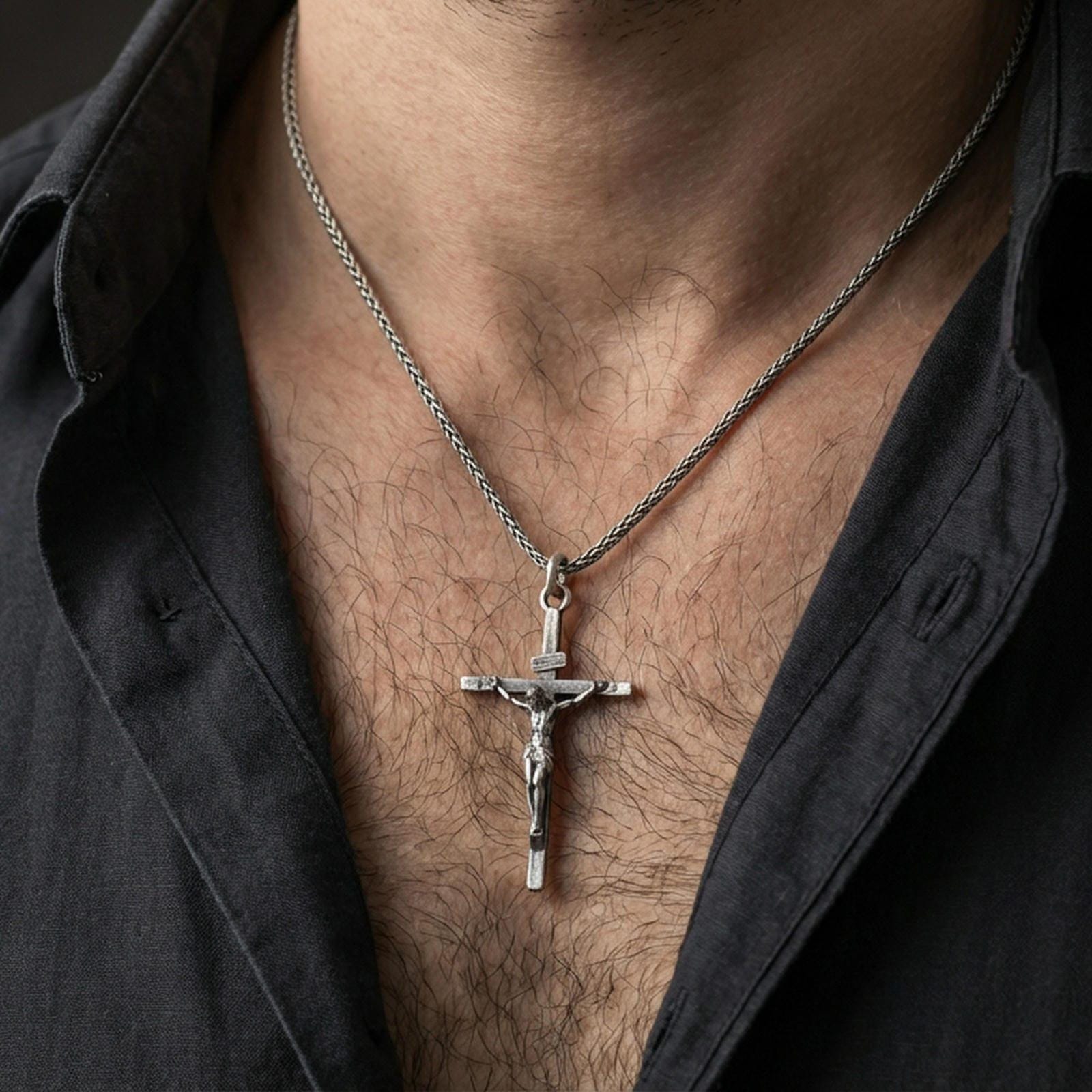 Oxidized sterling silver crucifix pendant worn on the neck, lifestyle image focusing on bold contrast, visible relief, and everyday faith styling.