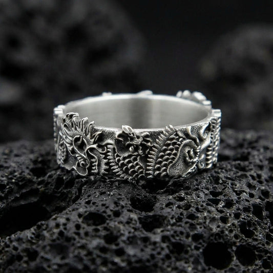 Oxidized sterling silver Japanese dragon band ring on volcanic stone, macro close-up emphasizing deep carving, scales, and high-contrast antique detailing.