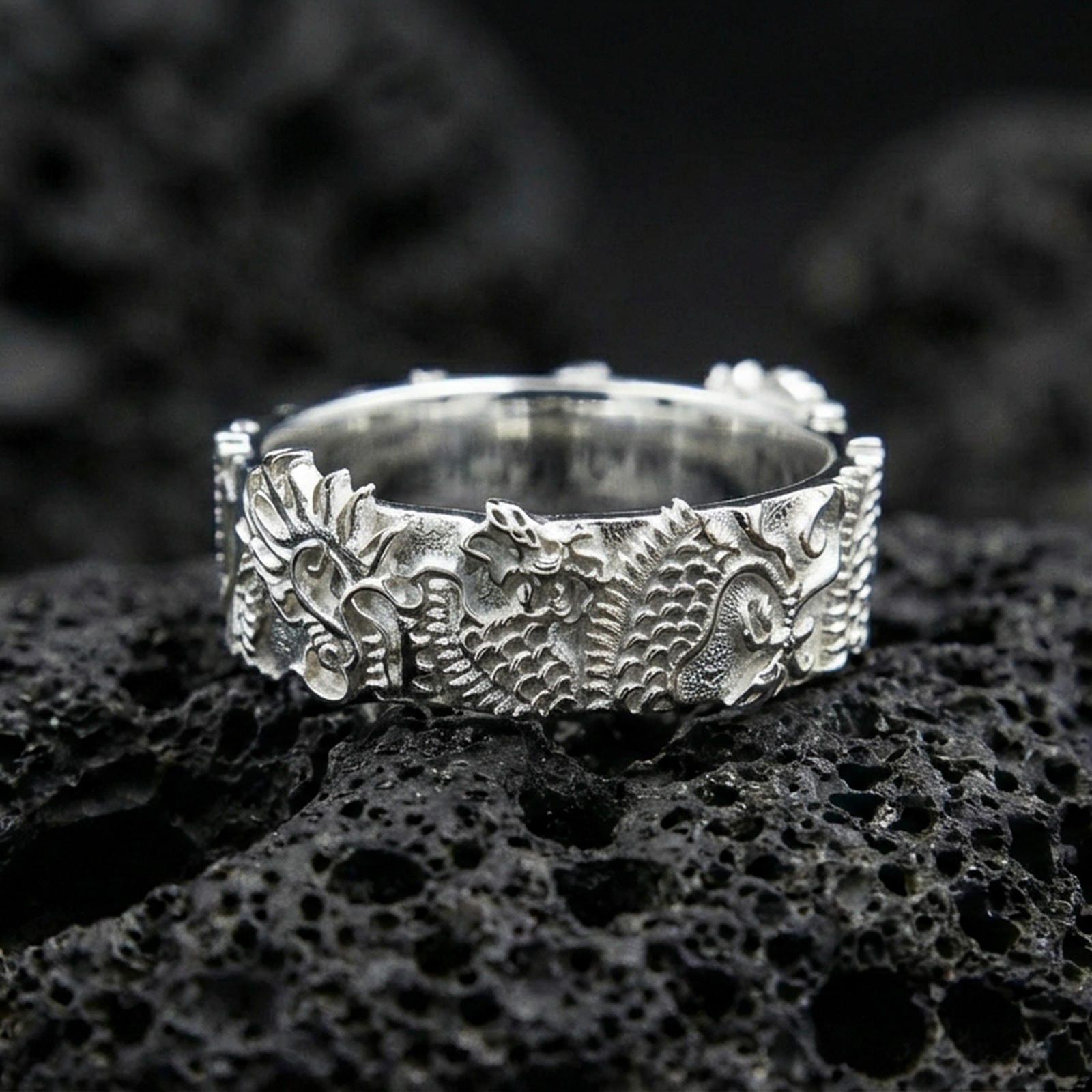 Polished silver Japanese dragon band ring on volcanic stone, macro shot highlighting crisp relief, refined edges, and bright reflective finish.