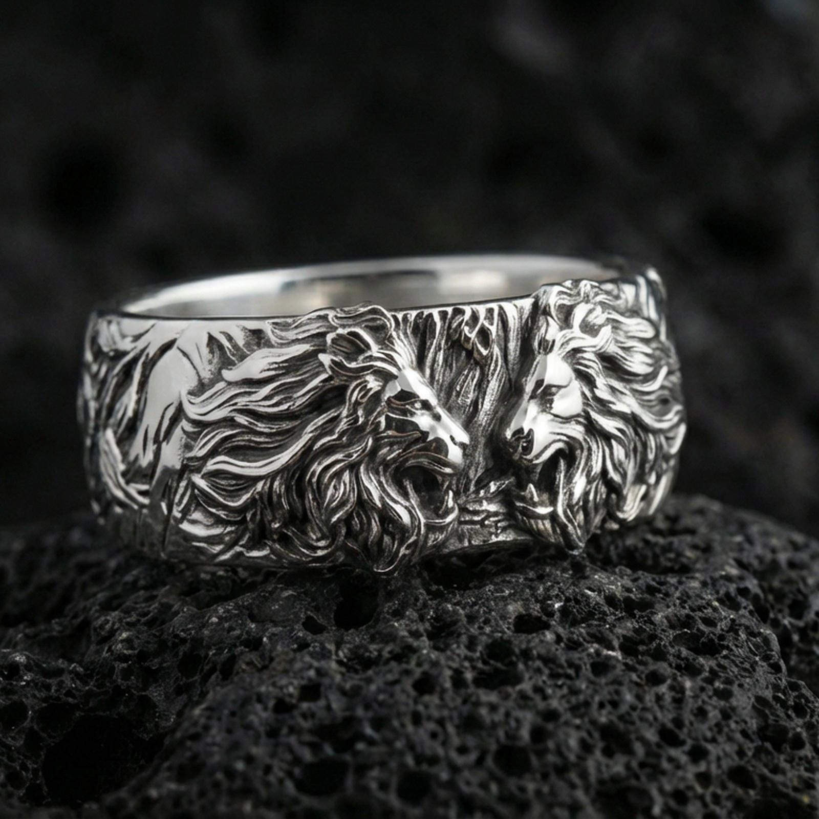 Polished silver lion head ring on volcanic stone, crisp macro photo emphasizing bright reflections, sharp facial detail, and clean band edges.