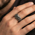 Load image into Gallery viewer, Oxidized sterling silver skull ring worn on the finger, lifestyle image focusing on bold gothic statement presence, antique depth, and rugged styling.
