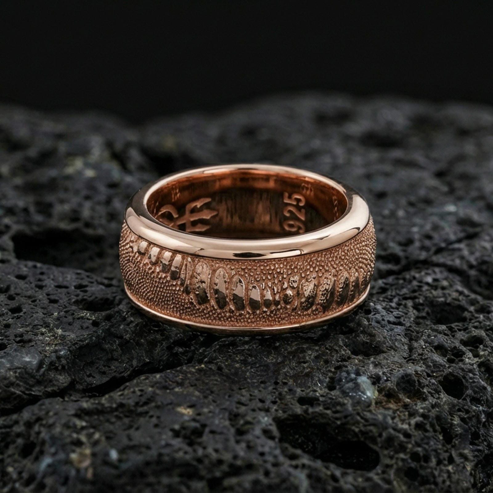 Rose gold plated lizard skin spinner ring on volcanic stone, refined macro close-up showcasing soft rose sheen over the scaled pattern and clean comfort-fit profile.