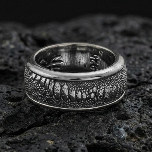 Oxidized sterling silver lizard skin spinner ring on volcanic stone, macro close-up highlighting reptile-scale texture and deep shadowed contrast on the rotating band.