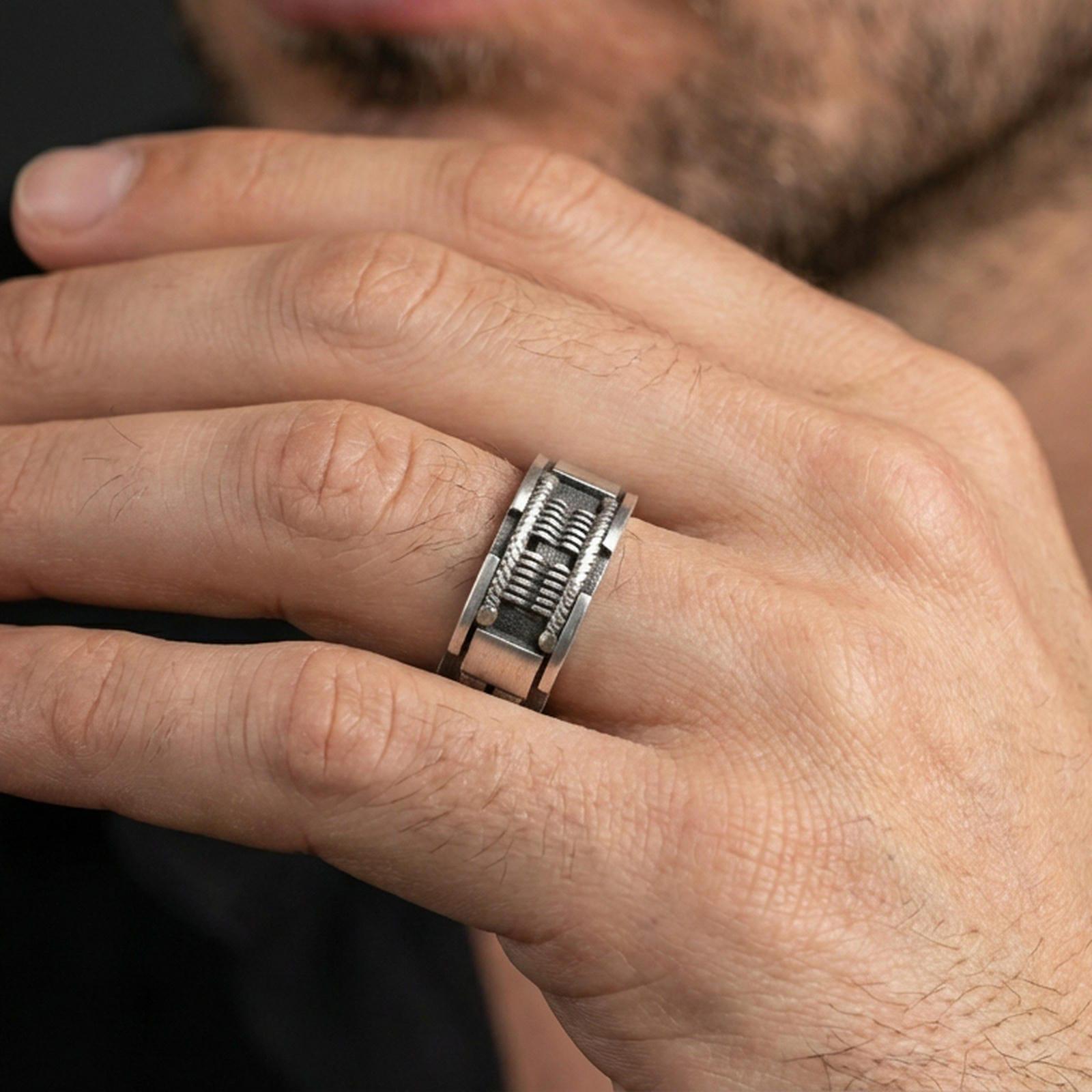 Oxidized sterling silver sci-fi band ring worn on the finger, lifestyle image focusing on rugged contrast, deep texture, and a modern industrial statement look.