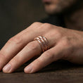 Load image into Gallery viewer, Rose gold plated layered studded band ring worn on the finger, lifestyle image highlighting elegant rose tone, stacked band depth, and refined contemporary styling.
