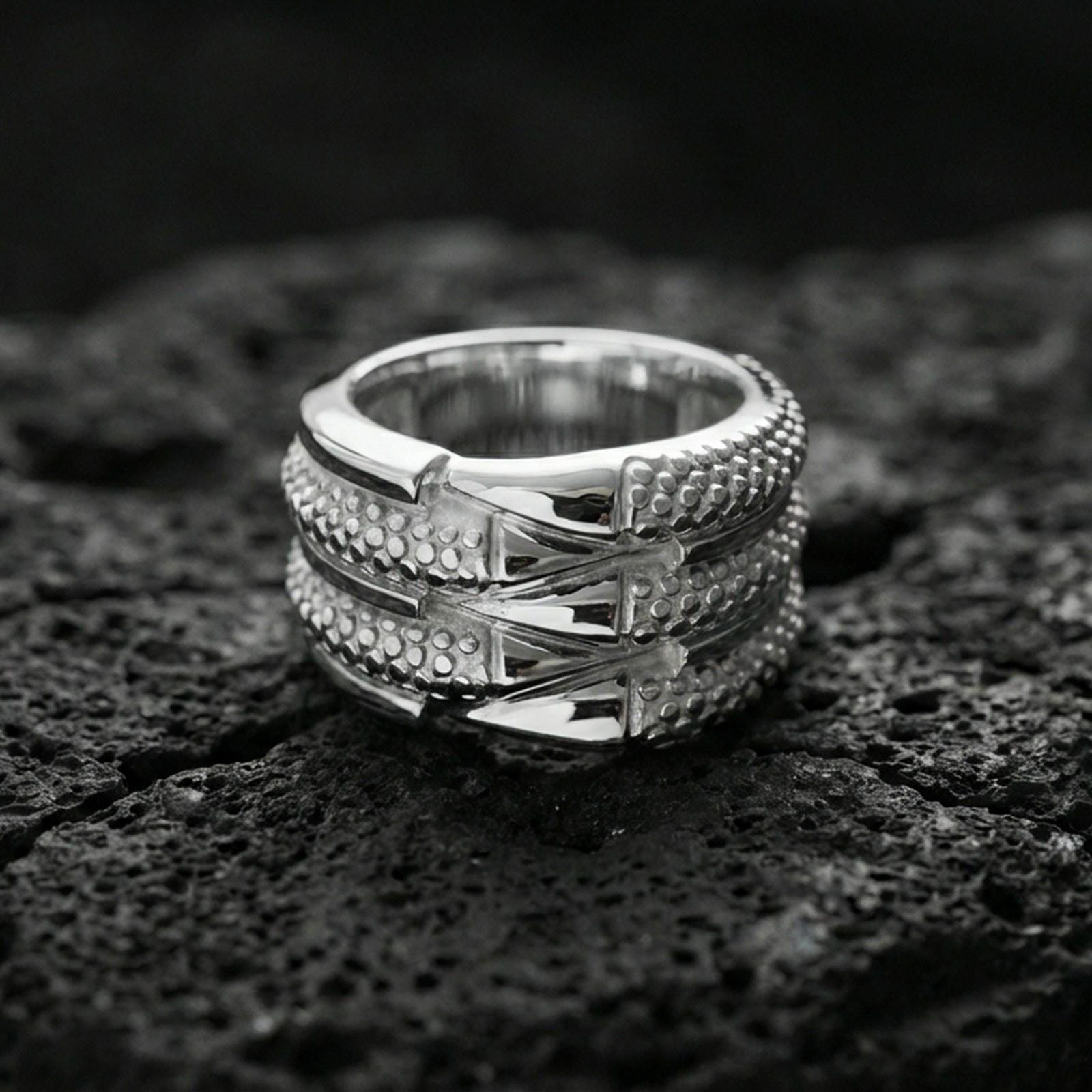 Polished silver layered studded band ring on volcanic stone, crisp macro shot emphasizing clean reflections, stacked structure, and precision dot detailing.