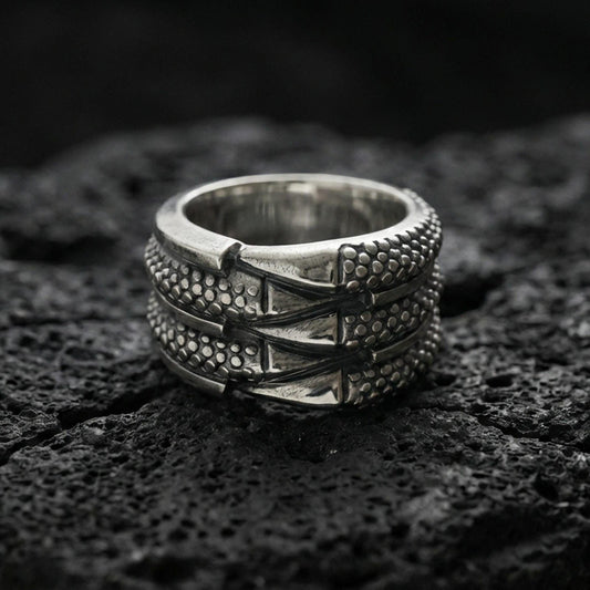 Oxidized sterling silver layered studded band ring on volcanic stone, macro close-up highlighting dotted texture panels and bold industrial ridge lines.