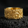 Load image into Gallery viewer, Gold plated dragon cloud band ring on volcanic stone, luxury macro shot capturing warm gold tone across the dragon body and flowing cloud patterns.
