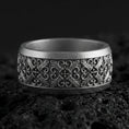 Load image into Gallery viewer, Oxidized sterling silver cross scrollwork band ring on volcanic stone, macro close-up showing deep darkened recesses and ornate vintage filigree detail.
