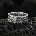 Load image into Gallery viewer, Polished silver quatrefoil cross band ring on volcanic stone, crisp macro photo highlighting bright shine, clean edges, and symmetrical scrollwork framing.
