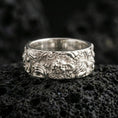 Load image into Gallery viewer, Polished silver guardian lion band ring on volcanic stone, crisp macro photo emphasizing bright reflective edges, sculpted mane texture, and clean ornamental scrollwork.
