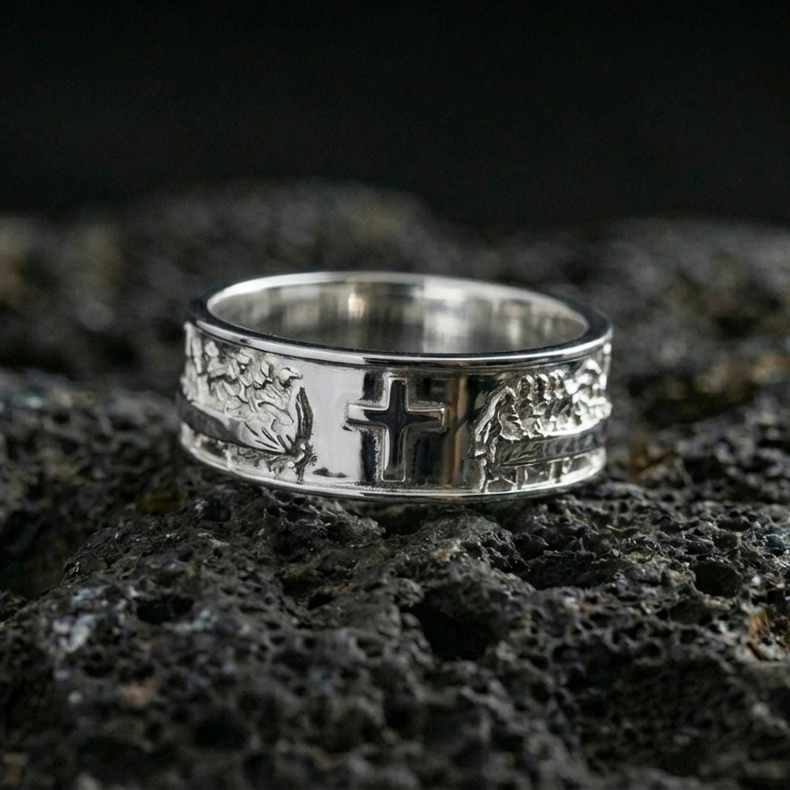 Polished silver cross band ring on volcanic stone, clean macro shot emphasizing bright reflective edges, smooth band finish, and sharp cross detail.