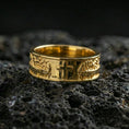 Load image into Gallery viewer, Gold plated cross band ring on volcanic stone, premium macro photo capturing warm gold tone on the raised cross and the surrounding engraved pattern.
