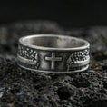 Load image into Gallery viewer, Oxidized sterling silver cross band ring on volcanic stone, macro close-up highlighting darkened recesses, raised cross centerpiece, and crisp relief texture.

