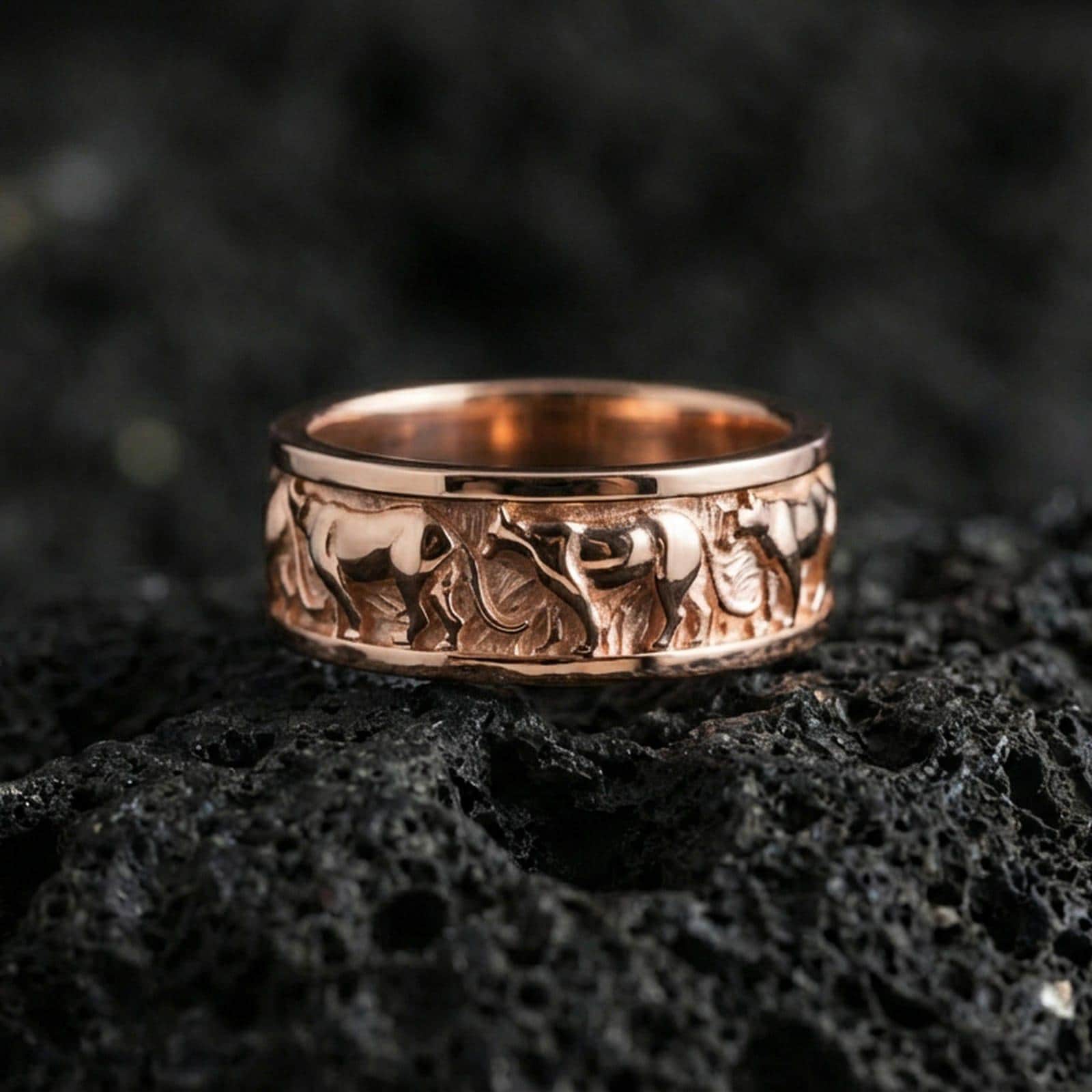 Rose gold plated horse band ring on volcanic stone, refined macro close-up showcasing soft rose warmth and the continuous horse-pattern band texture.