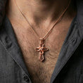 Load image into Gallery viewer, Rose gold plated gothic cross necklace with wrapped snake detail and refined symbolic form worn on the neck in a refined lifestyle shot with a warm and distinctive presentation
