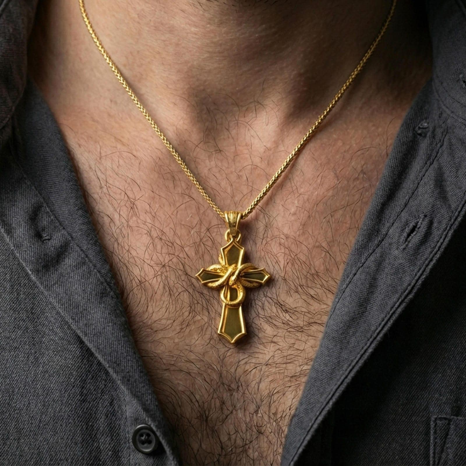 Gold plated snake cross pendant with sculpted serpent motif worn on the neck in a premium lifestyle composition with strong alternative jewelry styling