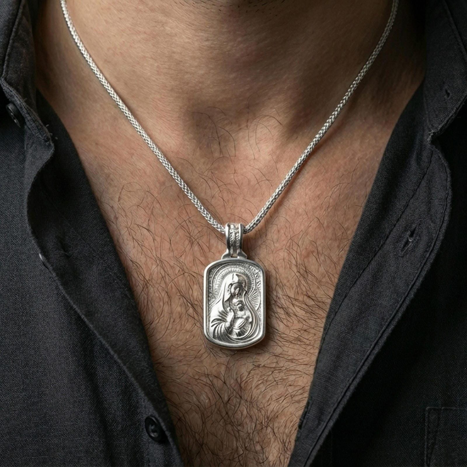 Polished silver Madonna and Child medallion worn on the neck in a close lifestyle frame, highlighting the detailed sacred portrait and refined halo accents