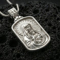 Load image into Gallery viewer, Polished silver Madonna and Child medallion with detailed mother and infant relief, radiant halo accents, and framed sacred silhouette placed on textured volcanic rock in a premium studio product shot
