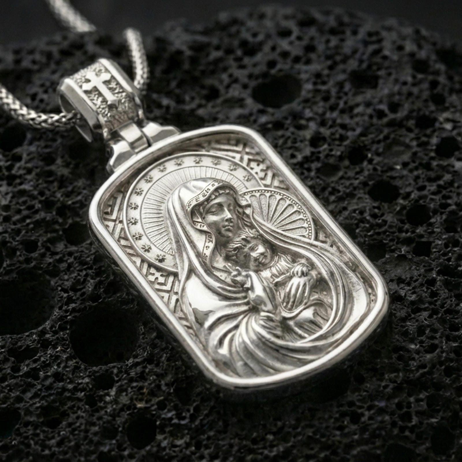 Polished silver Madonna and Child medallion with detailed mother and infant relief, radiant halo accents, and framed sacred silhouette placed on textured volcanic rock in a premium studio product shot