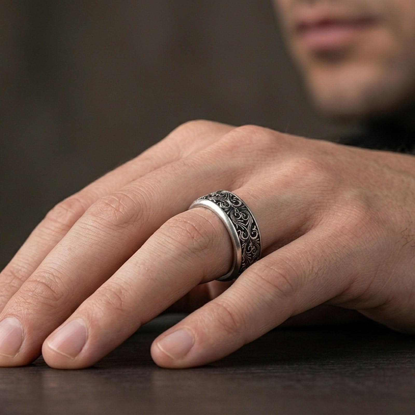 Ornate scrollwork sterling silver band ring worn on a finger, oxidized sterling silver look with high-contrast shadows that make the scrollwork stand out.