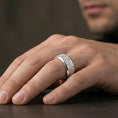 Load image into Gallery viewer, Ornate scrollwork sterling silver band ring worn on a finger, polished silver look with smooth reflections highlighting the engraved floral-scroll texture.
