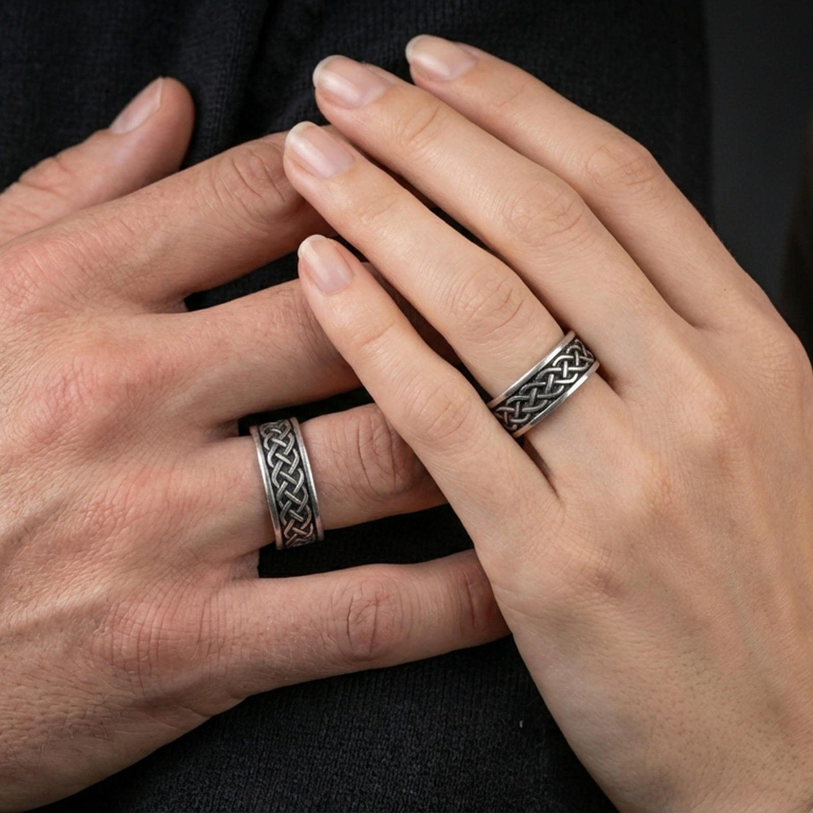 Sterling silver Celtic knot band ring worn on a finger, oxidized sterling silver look with strong contrast that makes the interlaced Celtic pattern read clearly.