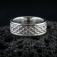 Load image into Gallery viewer, Sterling silver Celtic knot band ring on black volcanic stone, shown in a polished silver look with clean highlights across the interlaced knot pattern and smooth edges.
