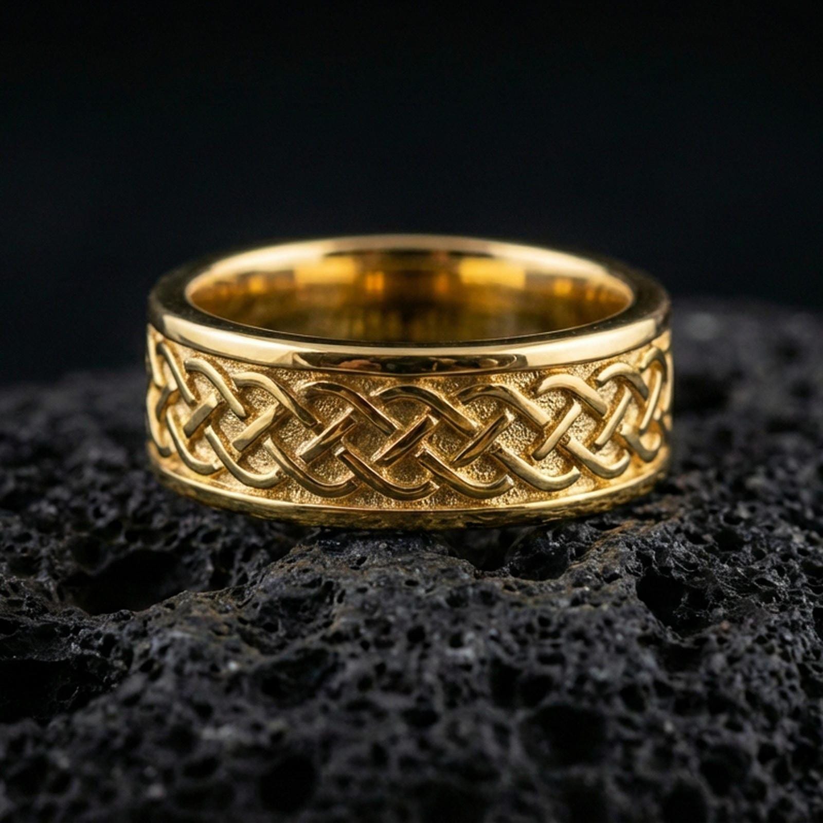 Sterling silver Celtic knot band ring on black volcanic stone, presented in a gold plated finish with warm shine that enhances the Celtic weave and dimensional relief.