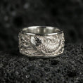 Load image into Gallery viewer, Koi fish spinner band ring on black volcanic stone, shown in a polished silver finish with clean highlights across the raised koi relief.
