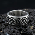 Load image into Gallery viewer, Celtic knot spinner band ring on black volcanic stone, shown in an oxidized sterling silver finish with deep darkened recesses highlighting the interlaced braid.
