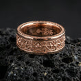 Load image into Gallery viewer, Gothic fleur-de-lis band ring on black volcanic stone, shown in a rose gold plated finish with a soft warm tone that enhances the engraved medieval geometry.
