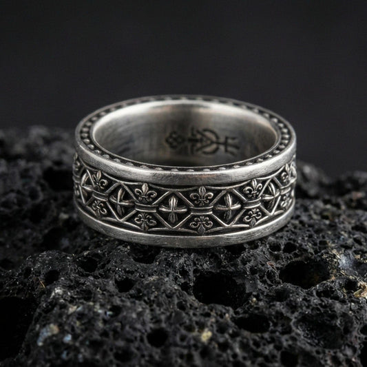 Gothic fleur-de-lis band ring on black volcanic stone, shown in an oxidized sterling silver finish with deep darkened recesses emphasizing the medieval lattice details.