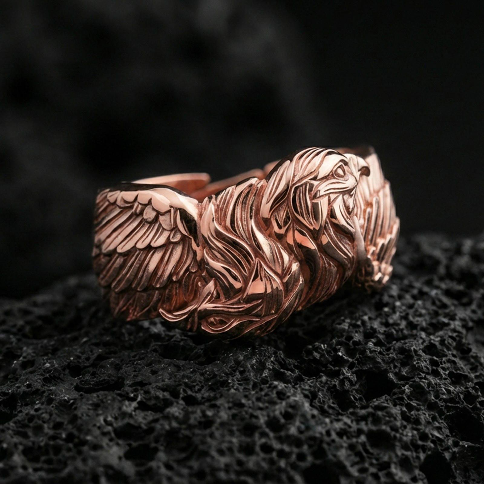 Eagle head and wing sterling silver ring on black volcanic stone, shown in a rose gold plated finish with a soft warm glow over the eagle head details.