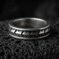 Load image into Gallery viewer, Industrial tread pattern sterling silver spinner ring on black volcanic stone, shown with an oxidized finish that emphasizes the recessed grooves and mechanical depth.
