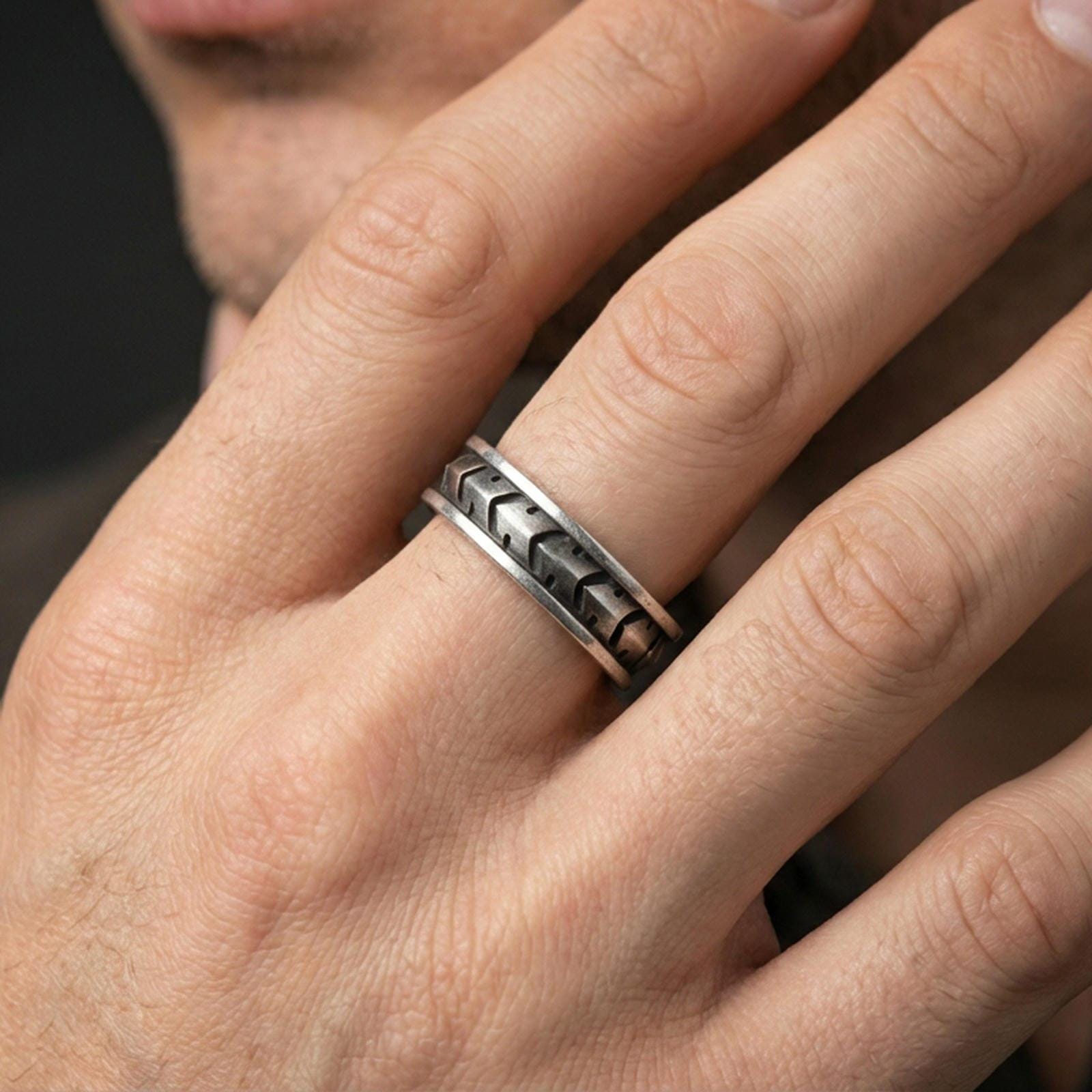 Industrial tread pattern sterling silver spinner ring worn on a finger, oxidized finish delivering strong contrast and a rugged mechanical look.