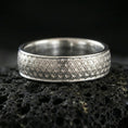 Load image into Gallery viewer, Polished silver textured band ring on black volcanic stone, crisp interwoven geometric pattern engraving, centered close-up studio lighting.
