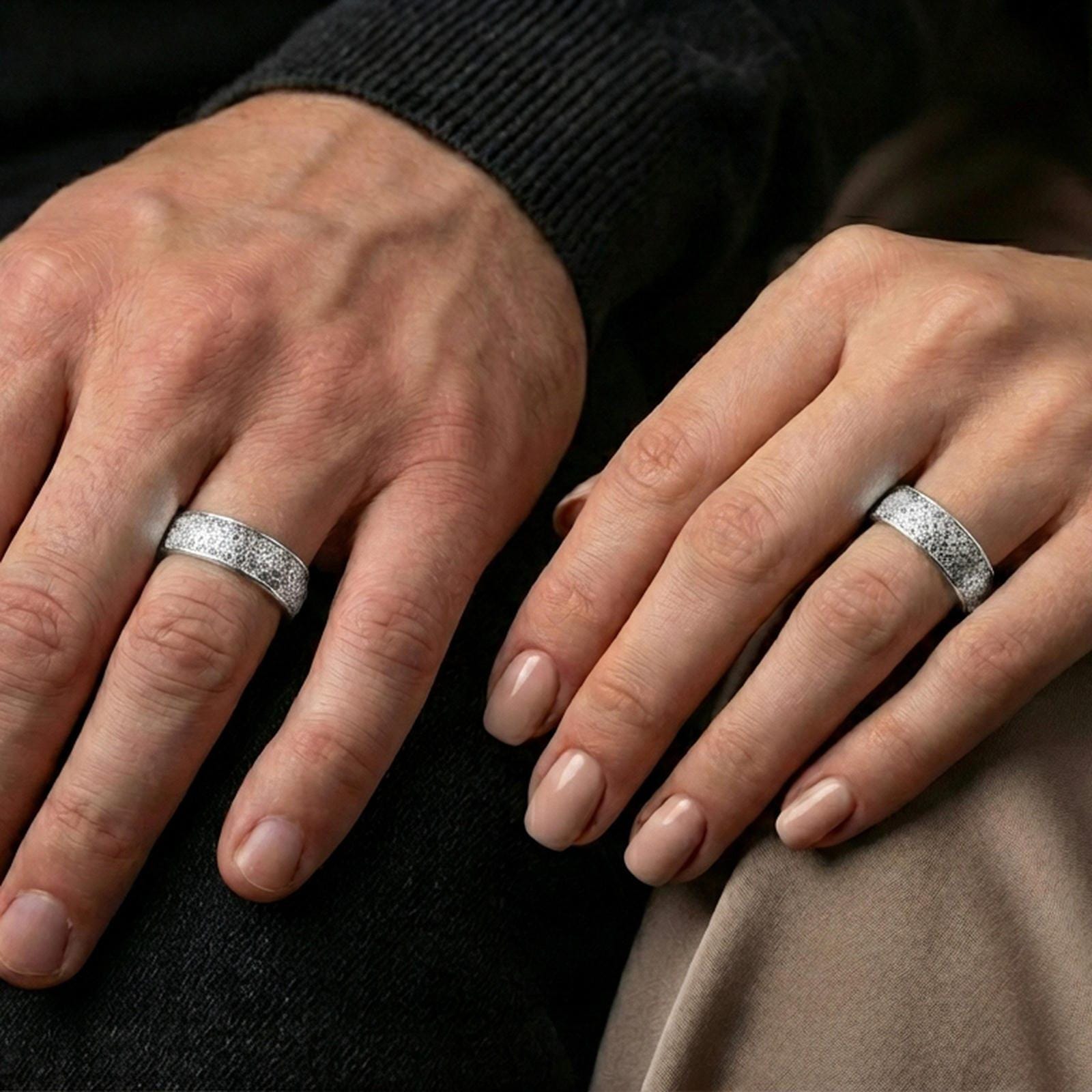 Polished silver textured band ring on finger, repeating geometric weave engraving, refined everyday wear close-up.