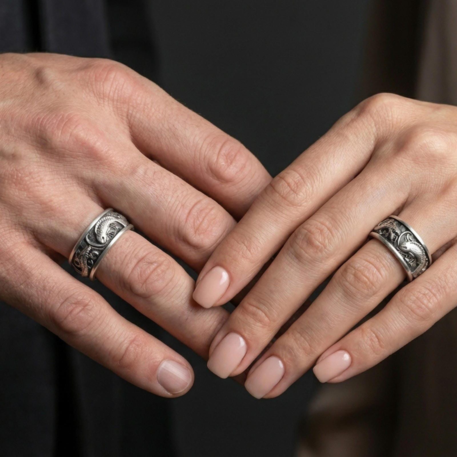 Oxidized sterling silver dragon and koi fish band worn on finger, raised Japanese motif detail, natural lifestyle hand shot with shallow depth of field.
