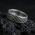 Load image into Gallery viewer, Oxidized sterling silver geometric lattice band ring on dark volcanic rock, diamond grid engraving with deep contrast, premium macro product shot.
