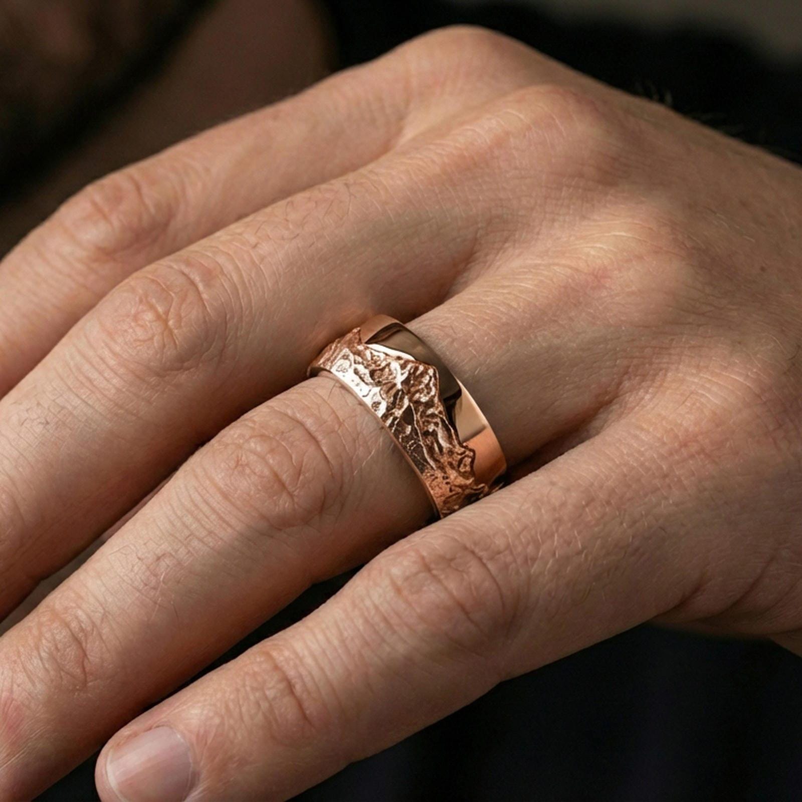 Rose gold plated mountain scene ring worn on finger, sculpted mountain relief with rugged terrain detail, elegant lifestyle wear shot.