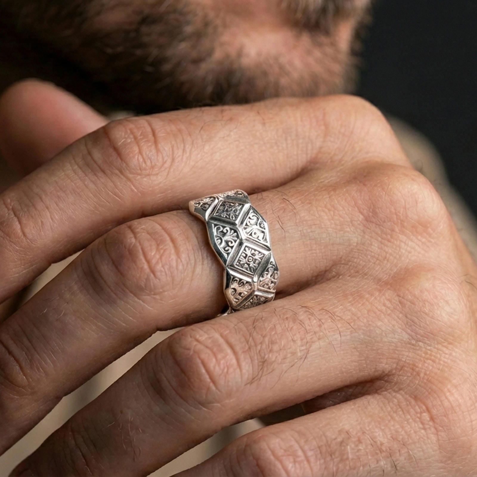 Polished silver engraved geometric band ring on finger, ornate filigree and diamond motif detail, refined everyday wear close-up.