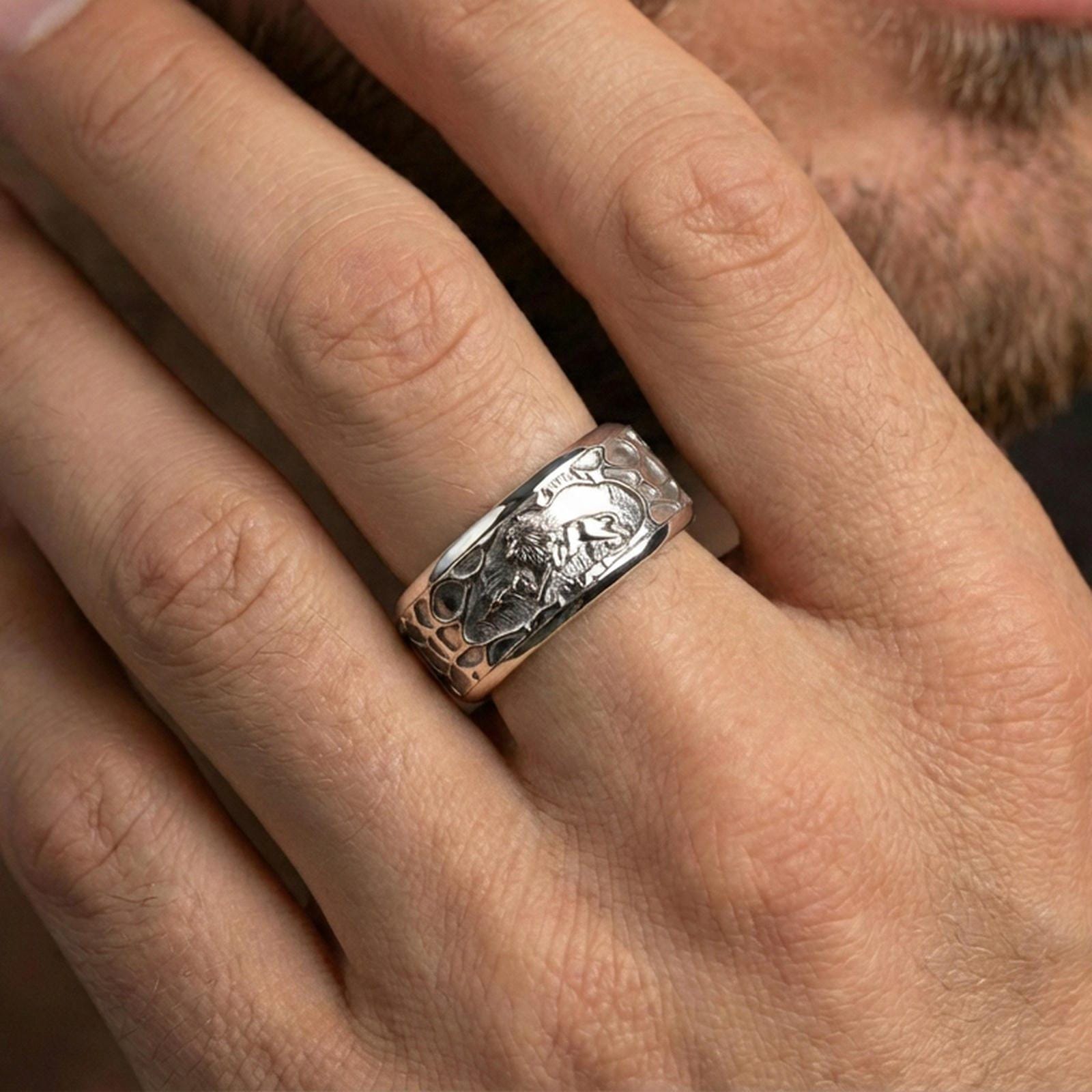 Polished silver lion scene spinner ring on finger, crisp lion relief and textured border detail, refined everyday wear close-up.